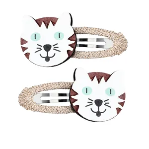 Détail de barrettes chat blanc en cuir avec texture tissée dorée pour petites filles