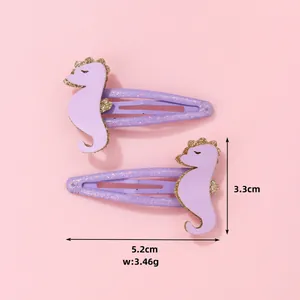 Détail de barrettes hippocampe violettes avec dimensions 5,2cm x 3,3cm sur fond rose