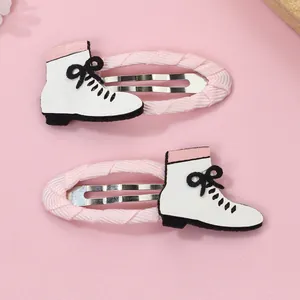 Detalle de pinzas para el cabello con cinta rosa y dijes de botas blancas con lazo