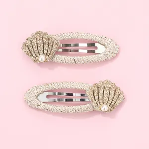 Detail of children's hair clips with pink glitter fabric, faux pearls and shell decor