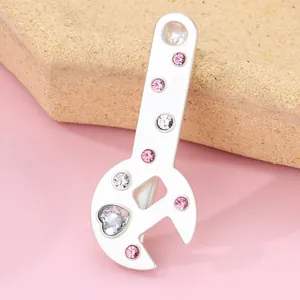 Macro view of wrench-shaped pendant with pink rhinestones and a heart-shaped zircon