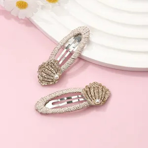 Detail view of shell-shaped hair clips with imitation pearls and gold glitter accents