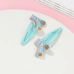 Detalle de pinzas para el cabello infantiles con forma de patines y ruedas doradas brillantes