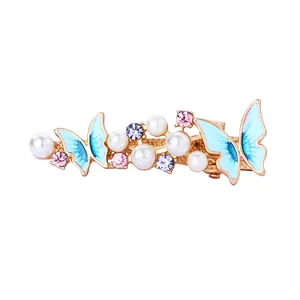 Detailed shot of golden butterfly hair clip with blue enamel, pearls and pink crystals