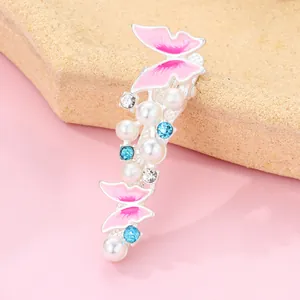 Detail of silver alloy butterfly hair clip with pink enamel pearls and blue rhinestones