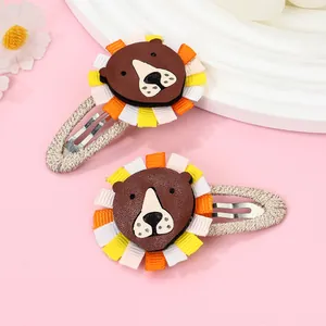 Detail of two handmade cartoon lion hair clips with ribbon manes and woven wrapped BB clips