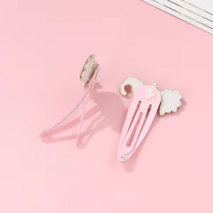 Gros plan sur les barrettes BB en métal rose avec décorations mignonnes en feutre blanc