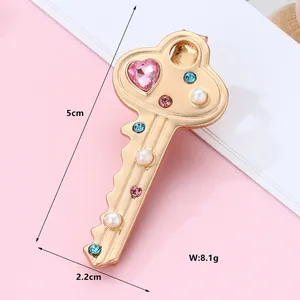 Detailed view of 5cm golden key hair clip with pink heart crystal and mixed gemstones
