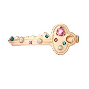 Detail of golden key hairpin with pink heart crystal and imitation pearls decoration