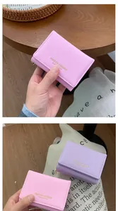 Detail of pink and purple cross-grain leather tri-fold wallets with golden lettering