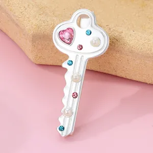 Macro shot of silver key brooch with pink heart crystal and pearls on soft backdrop