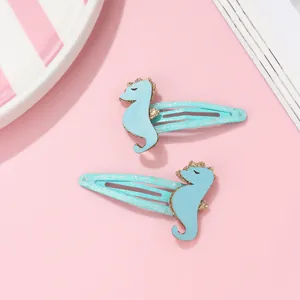 Détail des barrettes hippocampe bleu clair avec paillettes dorées sur fond rose