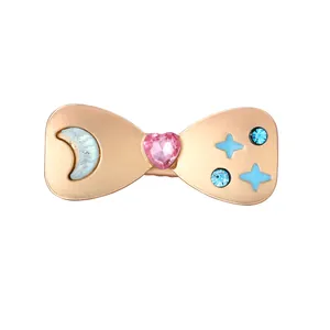Detail of rose gold bow hair clip with pink heart crystal and blue moon star motifs