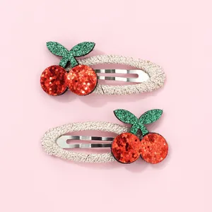Detail showing two sweet cherry hair clips with red glitter and green leaf sequins
