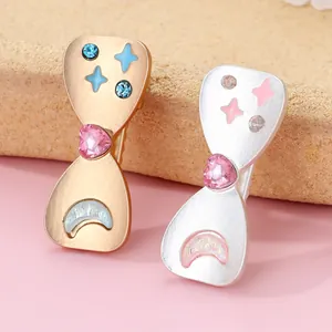Detail of heart hair clips with silver and gold finish, pink crystals and enamel stars