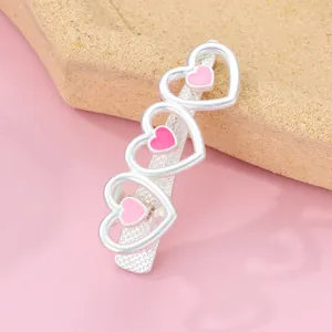 Detailed view of silver metal hair clip featuring three pink enamel heart designs