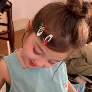 Close-up of sweet cherry embroidery hair clips with red glitter on a little girl