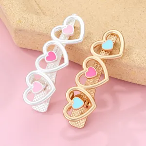 Detail view of heart-shaped alloy hair clips with pink and blue enamel on metal base