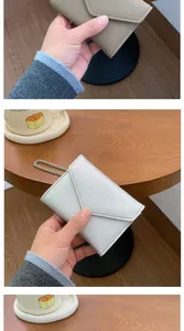 Detail of lychee pattern leather envelope mini wallets with metal chains in beige and white