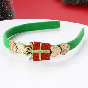 Dettaglio cerchietto natalizio verde con cuore glitterato e pacco regalo su piatto bianco