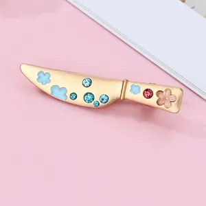 Detailed close-up of a gold kitchen knife hair clip with blue clouds and rhinestones