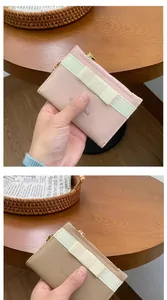 Close-up of pink and khaki zipper card wallets featuring a cream bow and gold hardware