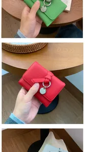 Detail of short leather wallet with litchi texture, metal ring and knot decoration