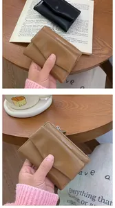 Detailed view of compact PU leather envelope wallets in brown and black on wooden desk