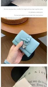 Detailed view of light blue leather mini wallet featuring tie decor and a long shoulder strap