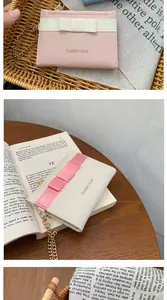 Detailed view of women's mini wallet with bow decoration and classic gold zipper closure