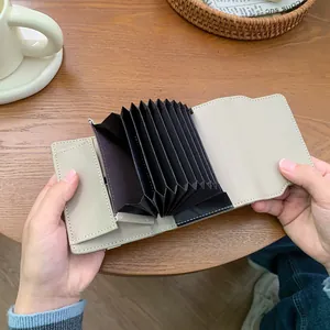 Portacarte a fisarmonica minimalista in pelle beige con slot multipli su un tavolo