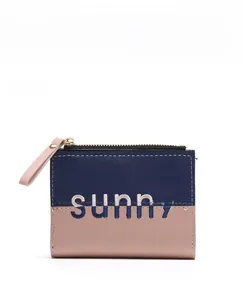 Detail showing contrast navy and pink PU leather wallet with 'sunny' metal lettering