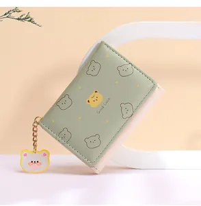Detalle de mini cartera plegable con estampado de oso y amuleto Good Luck dorado