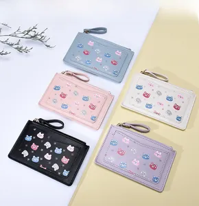 Flat lay of colorful PU leather coin purses with cute cartoon bear prints and wrist straps