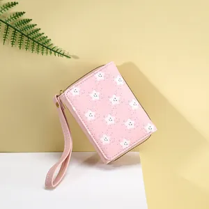 Detailed view of pink compact wallet featuring star pattern and wrist strap
