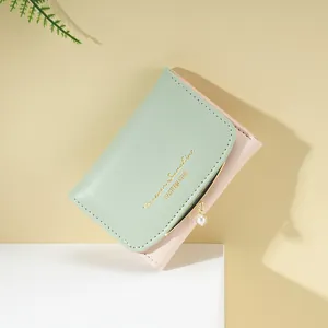 Detail of mint green and pink PU leather wallet with gold lettering and pearl charm