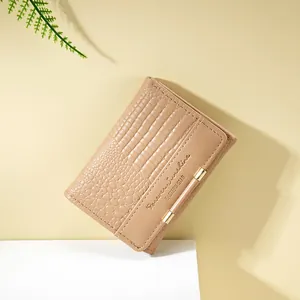 Dettaglio del portafoglio beige in finta pelle di coccodrillo con finiture dorate e logo