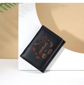 Détail de la broderie sur un portefeuille en cuir noir avec des motifs de biscuits
