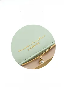Detail of mint green and pink PU leather wallet with pearl charm and gold lettering