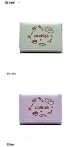 Détail de petits portefeuilles avec broderie cookies et fentes pour cartes en vert et violet