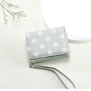 Detail of light green tri-fold wallet with star smiley patterns and a wrist strap