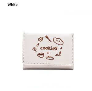 Détail d'un petit portefeuille blanc en cuir avec broderie mignonne de biscuits et café