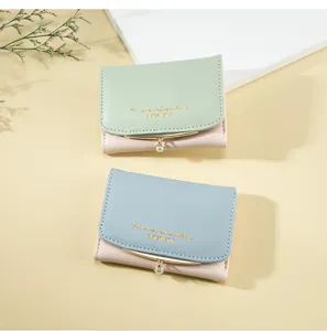 Close-up of pastel faux leather short wallets with pearl charms and gold lettering details