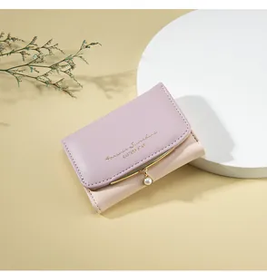 Detail of lavender leather wallet featuring gold hardware and a delicate pearl pendant
