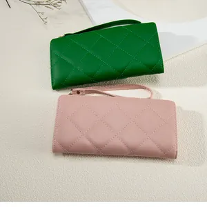 Detail of long quilted PU leather wallets in dark green and pink with wrist straps