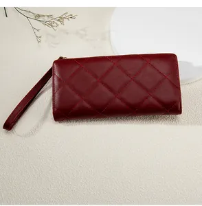 Macro shot of burgundy quilted leather wallet featuring classic diamond stitching and wristlet