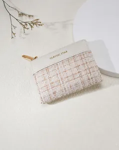Detail of tweed and cream leather wallet with quilted pattern and gold zipper