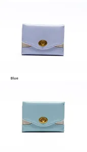Dettaglio di portafogli corti blu e lavanda con chiusura a rotazione dorata e glitter argento