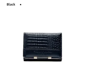 Macro detail of black crocodile pattern leather wallet with gold metal clasp closure