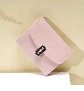 Detalle de mini cartera rosa claro con hebilla plateada estilo maquinilla y costuras